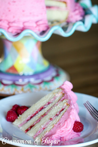 Raspberry cake is an almond scented white cake layered with raspberry buttercream and raspberry jam, with no artificial coloring. The perfect cake to celebrate any special occasion, especially Valentine's Day! Recipe shared with permission granted by Lucy Burdette, author of Fatal Reservations. 