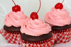 Rich chocolate cola cupcakes with the sweetness of cherries, are topped with super creamy cherry cola buttercream frosting. One bite will make you feel like you're sitting in an old-fashioned soda fountain! Recipe shared with permission granted by Jenn McKinlay, author of VANILLA BEANED.