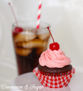 Rich chocolate cola cupcakes with the sweetness of cherries, are topped with super creamy cherry cola buttercream frosting. One bite will make you feel like you're sitting in an old-fashioned soda fountain! Recipe shared with permission granted by Jenn McKinlay, author of VANILLA BEANED.