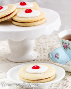 Empire Biscuits are flaky shortbread cookies that sandwich tart raspberry preserves and are then topped with sweet icing and colorful maraschino cherries. The perfect accompaniment to afternoon tea!