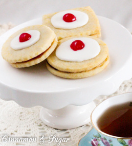 Empire Biscuits are flaky shortbread cookies that sandwich tart raspberry preserves and are then topped with sweet icing and colorful maraschino cherries. The perfect accompaniment to afternoon tea!