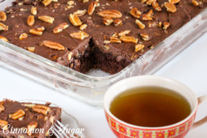 Spanish Chocolate Cake is a rich chocolate cake that is topped with a fudgy, pecan-laden frosting. A hint of warm cinnamon makes this a special dessert. Recipe from S.C. Perkins, author of MURDER ONCE REMOVED.