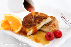 Stuffed French Toast are slices of French bread stuffed with orange zest and cream cheese. Paired with Honey Orange Syrup makes it a perfect breakfast! Recipe shared with permission granted by Kate Carlisle, author of THE BOOK SUPREMACY.