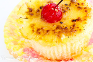 A rich, buttery pineapple cake topped with a caramelized pineapple ring and maraschino cherry make Pineapple Upside-Down Cupcakes perfect for hot summer months! Recipe shared with permission granted by Jenn McKinlay, author of DYING FOR DEVIL'S FOOD.