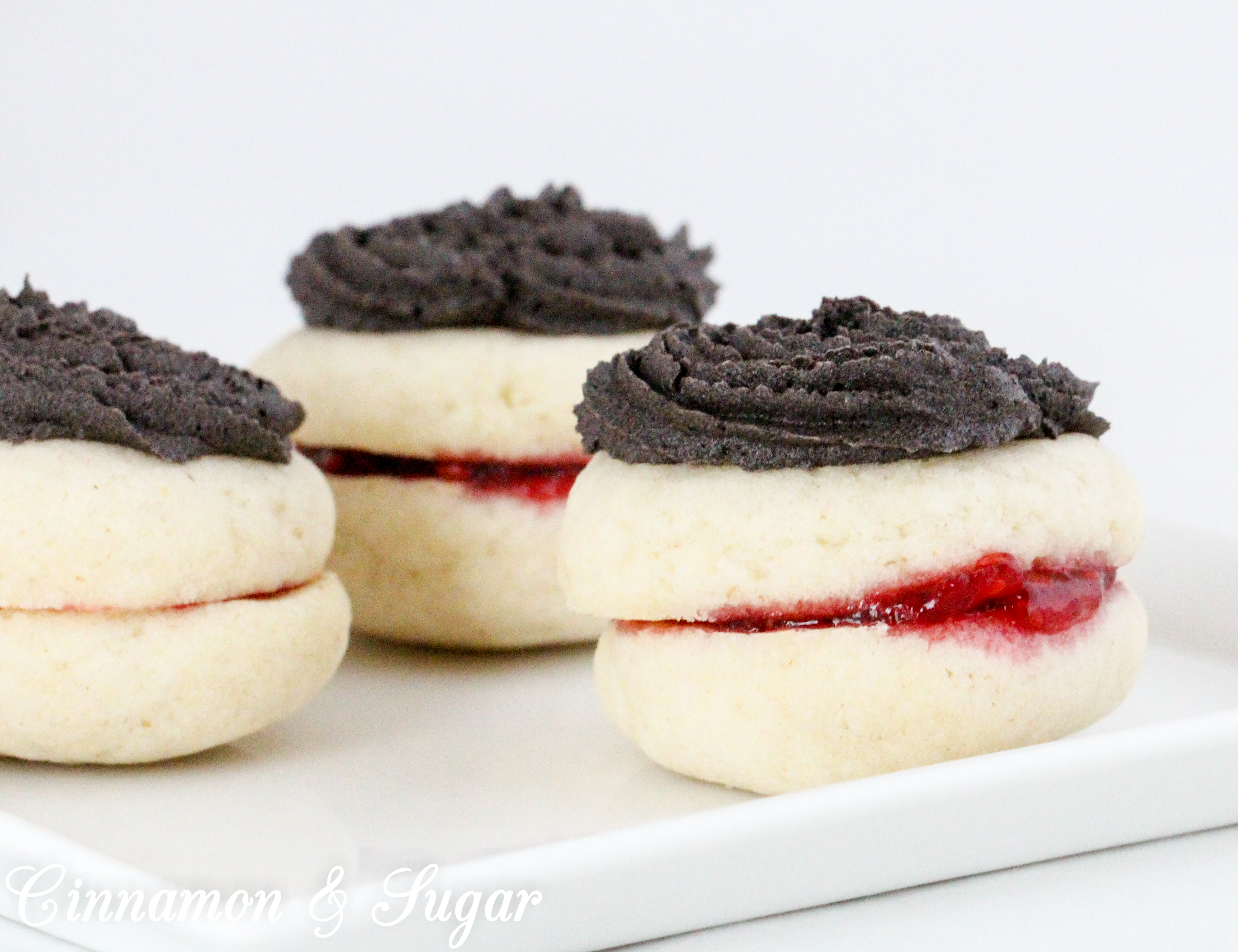 Mom’s Antoinettes are buttery, almond-flavored shortbread-style cookies that are sandwiched around raspberry jam and topped with dark chocolate buttercream. Recipe shared with permission granted by Ellie Alexander, author of A CUP OF HOLIDAY FEAR. 