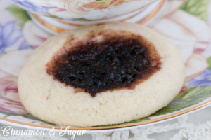 Mulberry Thumbprint Cookies are a shortbread-style cookie with a dollop of mulberry jam providing a beautiful dark purple jewel in the middle of the baked cookie. Recipe shared with permission granted by Sharon Farrow, author of MULBERRY MISCHIEF. 