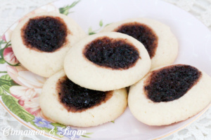 Mulberry Thumbprint Cookies are a shortbread-style cookie with a dollop of mulberry jam providing a beautiful dark purple jewel in the middle of the baked cookie. Recipe shared with permission granted by Sharon Farrow, author of MULBERRY MISCHIEF. 