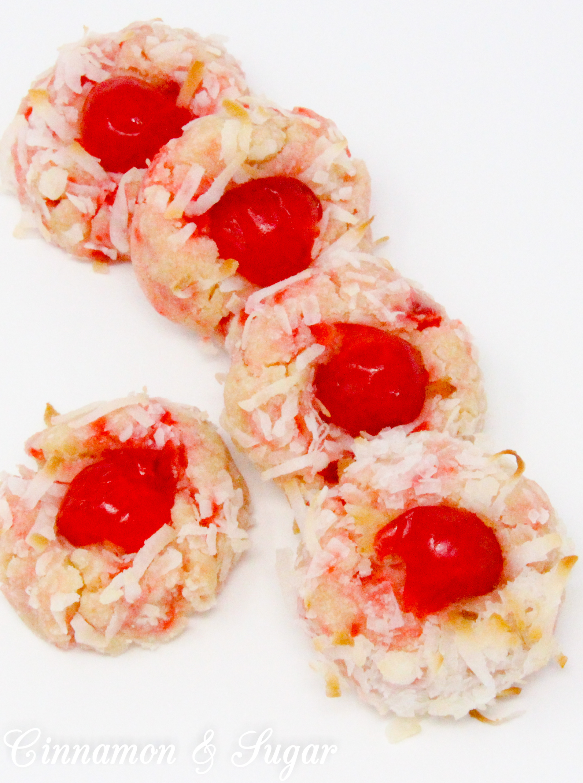With snowy white coconut and glistening red cherries, shortbread-style Yuletide Coconut Cherry Cookies add holiday cheer to Christmas cookie platters. Recipe created by Cinnamon & Sugar for Deborah Garner, author of YULETIDE AT MOONGLOW. 