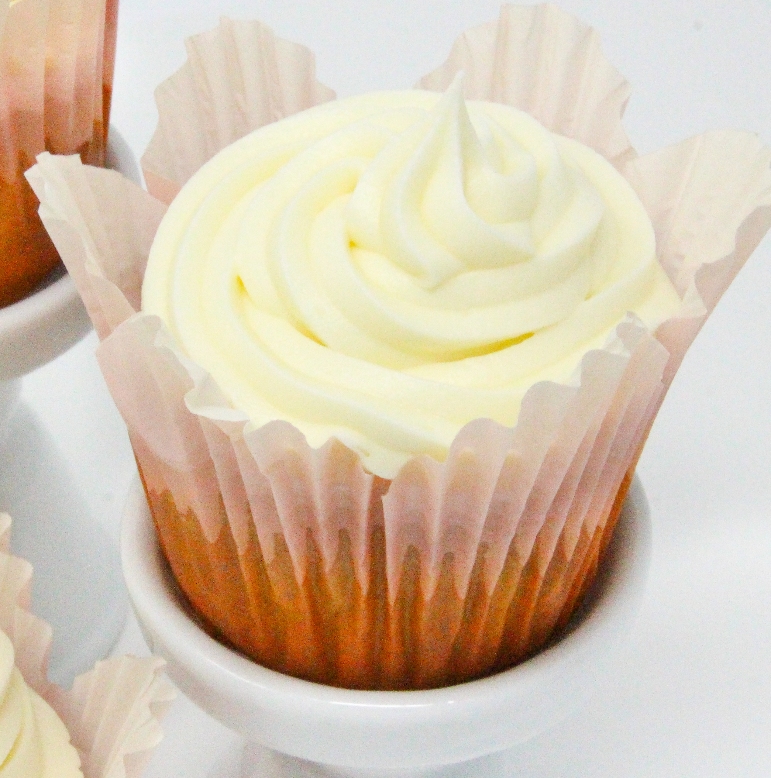 Carrot Raisin Muffins are super moist without using a lot of fat, thanks to the generous amount of carrots. With the addition of sweet raisins, crunchy walnuts, and mounds of cream cheese frosting swirled over the tops, these make for a delicious breakfast or snack, or even a delectable dessert! Recipe shared with permission granted by Darci Hannah, author of MURDER AT THE BEACON BAKESHOP.