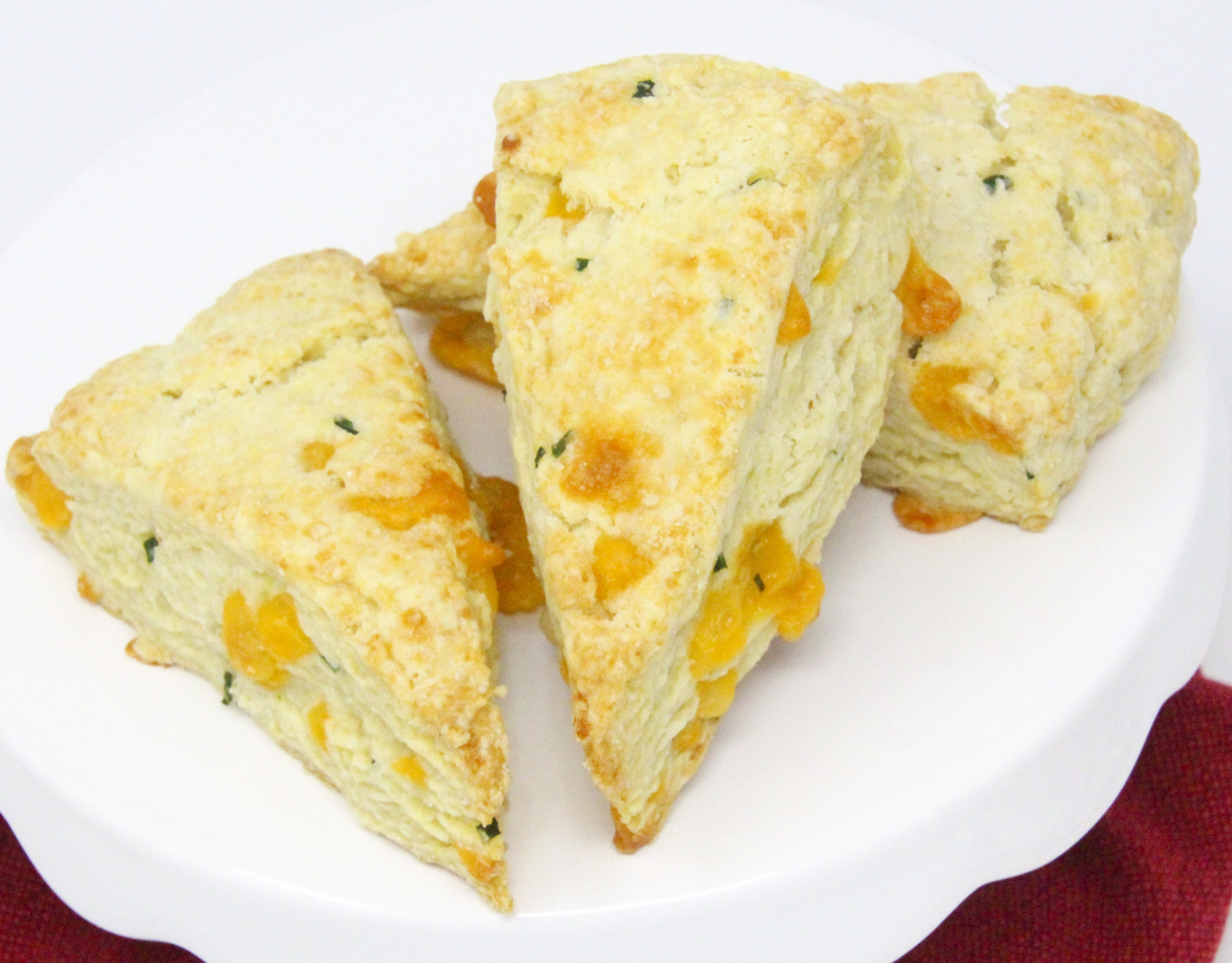 A delectable combination of flaky pastry, two kinds of cheese, and chives, Savory Cheese Scones are the perfect accompaniment to serve with a warming bowl of soup or even used as sandwich bread for lunch or a light supper. Recipe shared with permission granted by Kate Carlisle, author of LITTLE BLACK BOOK. 