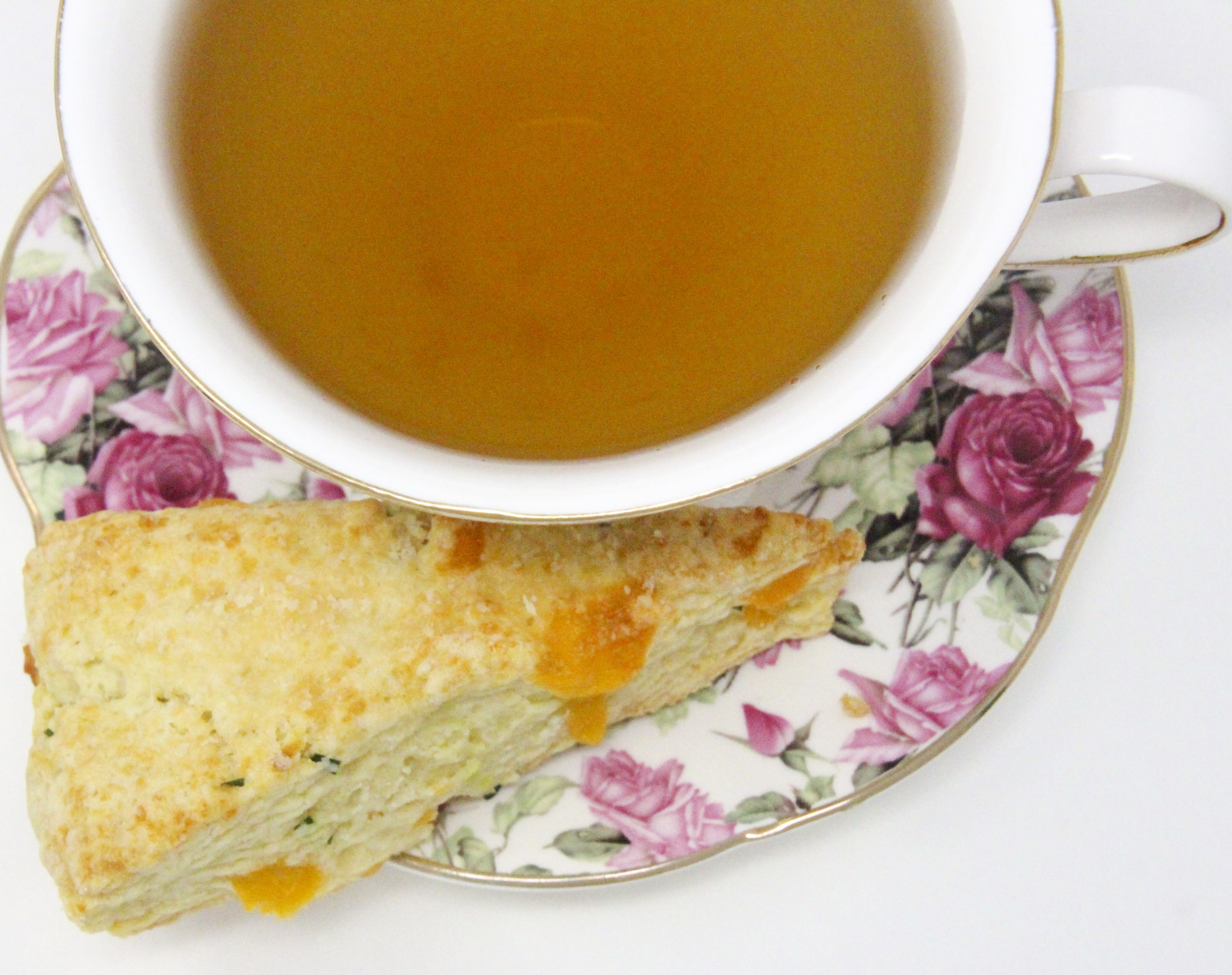 A delectable combination of flaky pastry, two kinds of cheese, and chives, Savory Cheese Scones are the perfect accompaniment to serve with a warming bowl of soup or even used as sandwich bread for lunch or a light supper. Recipe shared with permission granted by Kate Carlisle, author of LITTLE BLACK BOOK. 