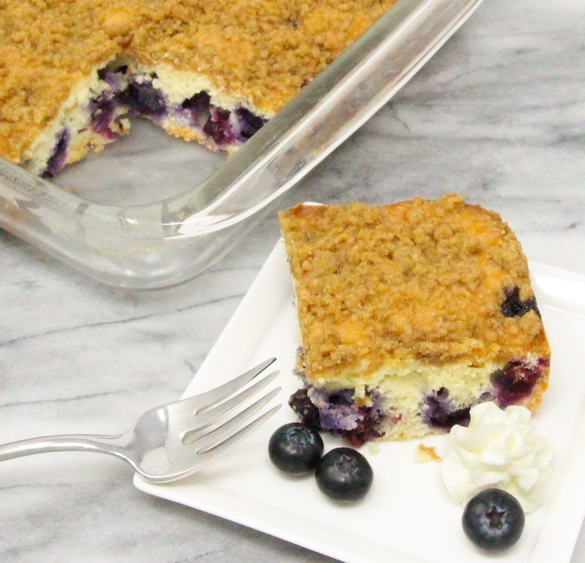 Blueberry Coffee Cake with Crumble is chock full of fresh blueberries in a tender vanilla cake. The cinnamon, brown sugar-based crumble adds both flavor and a pleasing crunchy texture. Recipe shared with permission granted by Krista Davis, author of A COLORFUL SCHEME. 