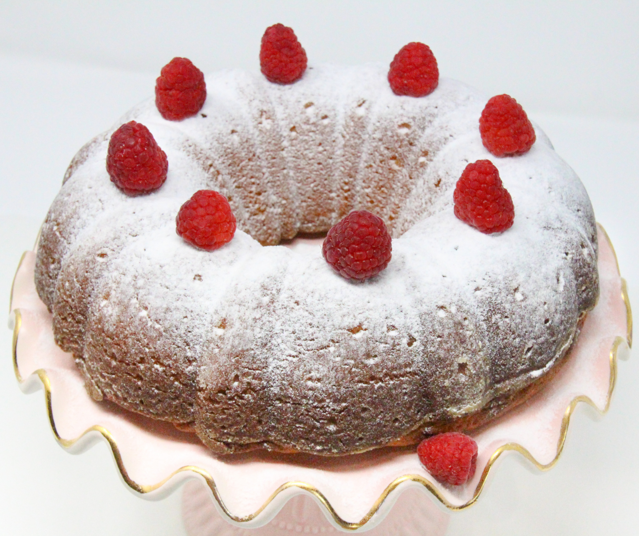 Portuguese Yogurt Cake is moist with a delicate flavor lending itself to versatility by swirling in your favorite jam or chocolate chips. With a quick sprinkle of powdered sugar and a handful of fresh raspberries for garnish, this makes a delicious dessert to serve on any occasion. Recipe shared with permission granted by Mary Jane Maffini, author of DEATH PLANS A PERFECT TRIP. 