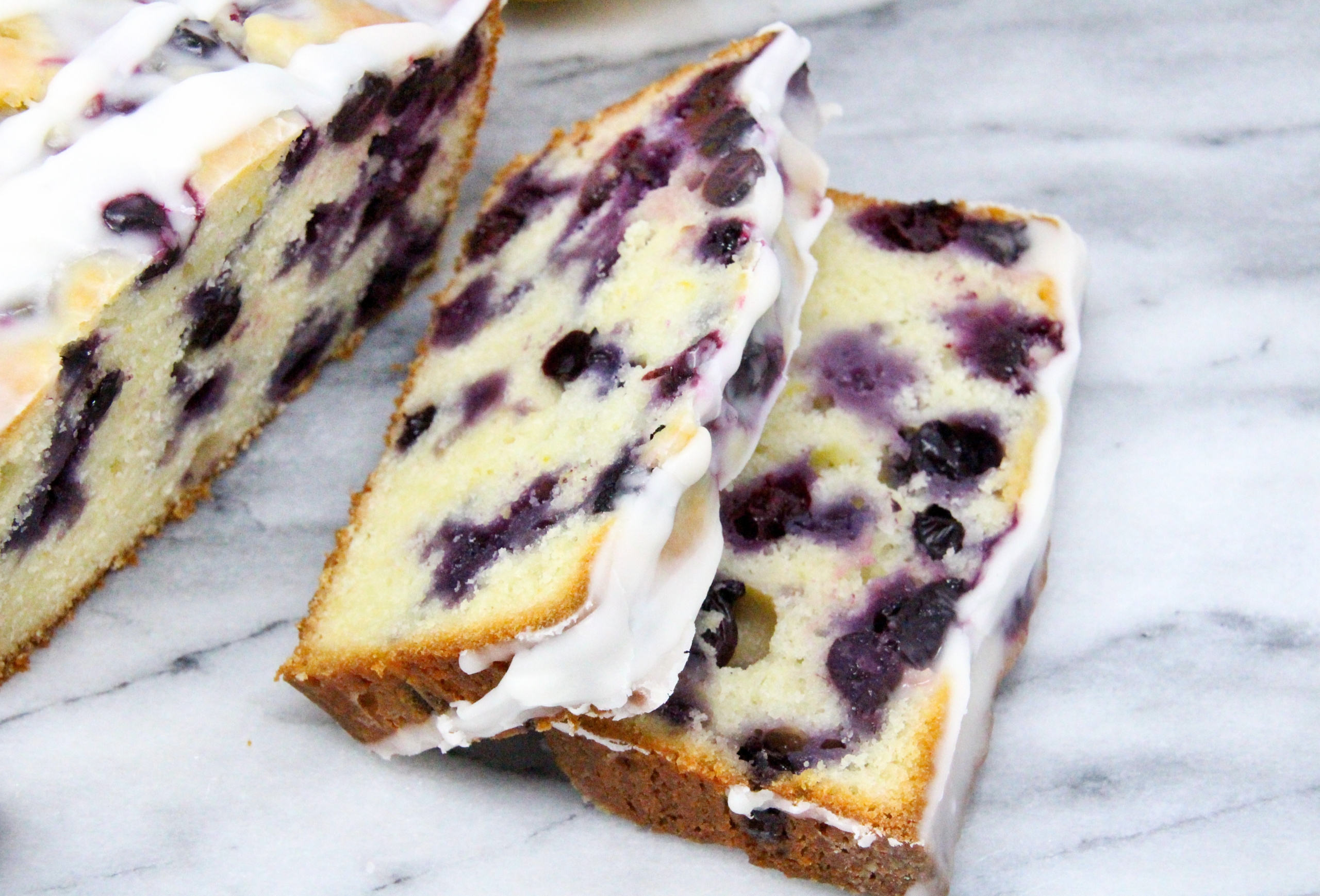 Blueberry Lemon Bread is a delectable tender and moist bread with plump juicy blueberries studded throughout and a sweet-tart lemony glaze. Recipe shared with permission granted by Darci Hannah, author of MURDER AT THE BLUEBERRY FESTIVAL. 