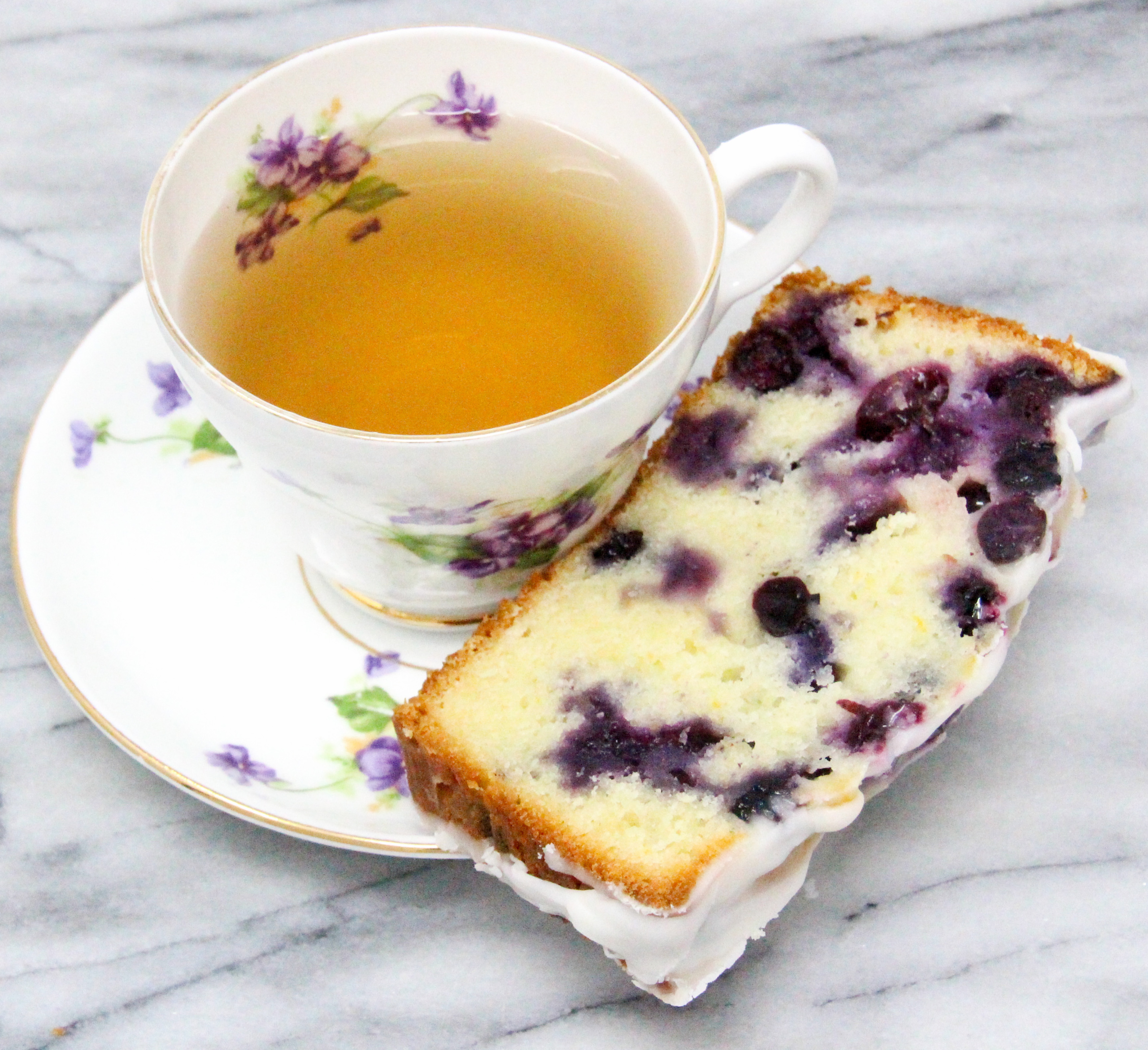 Blueberry Lemon Bread is a delectable tender and moist bread with plump juicy blueberries studded throughout and a sweet-tart lemony glaze. Recipe shared with permission granted by Darci Hannah, author of MURDER AT THE BLUEBERRY FESTIVAL. 