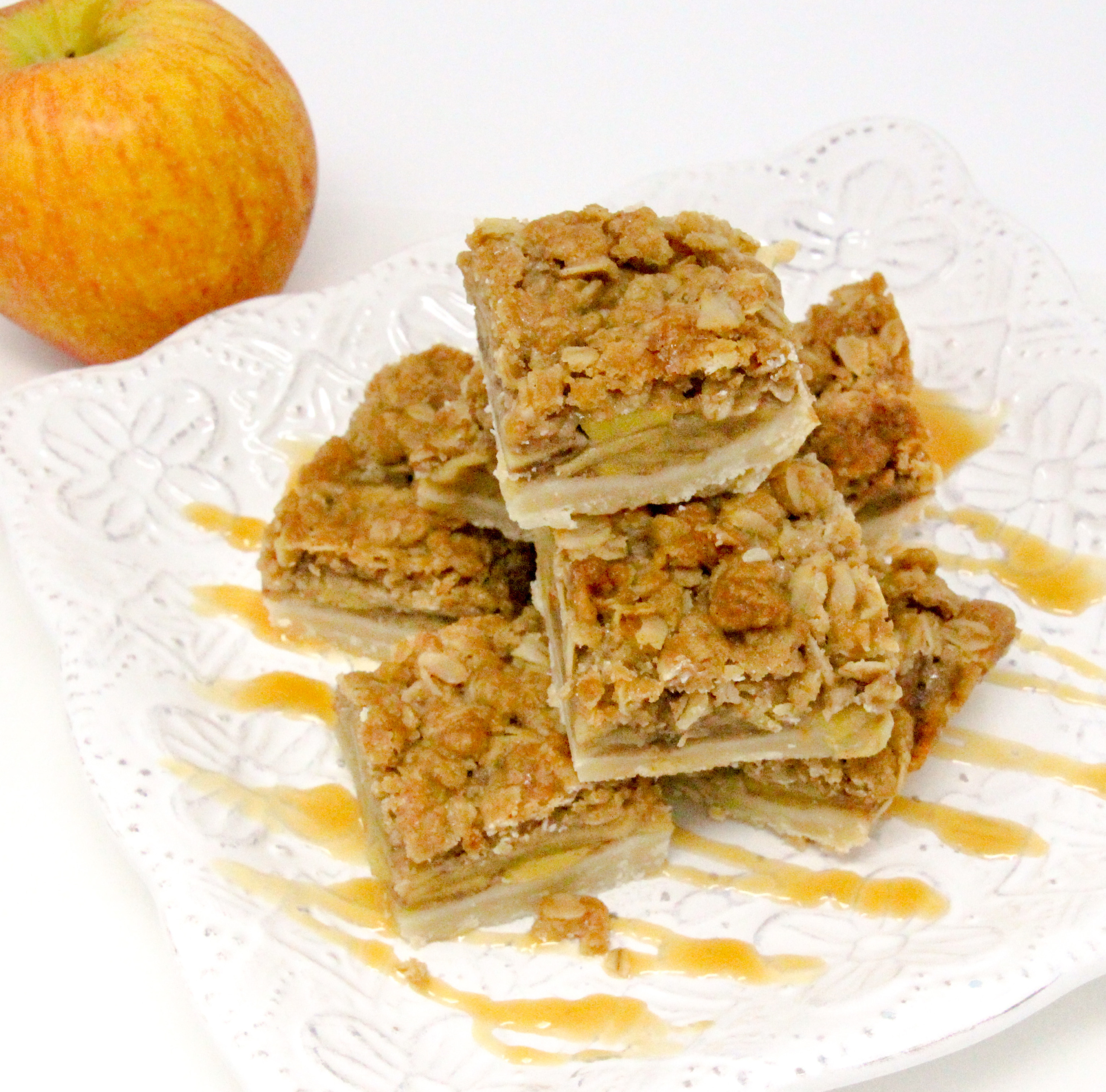 With a pastry base, a filling of spiced apples, and a crunchy oat topping, Caramel Apple Pie Bars are a delicious taste of autumn! Recipe from BUTTERCREAM BETRAYAL by Kim Davis. 