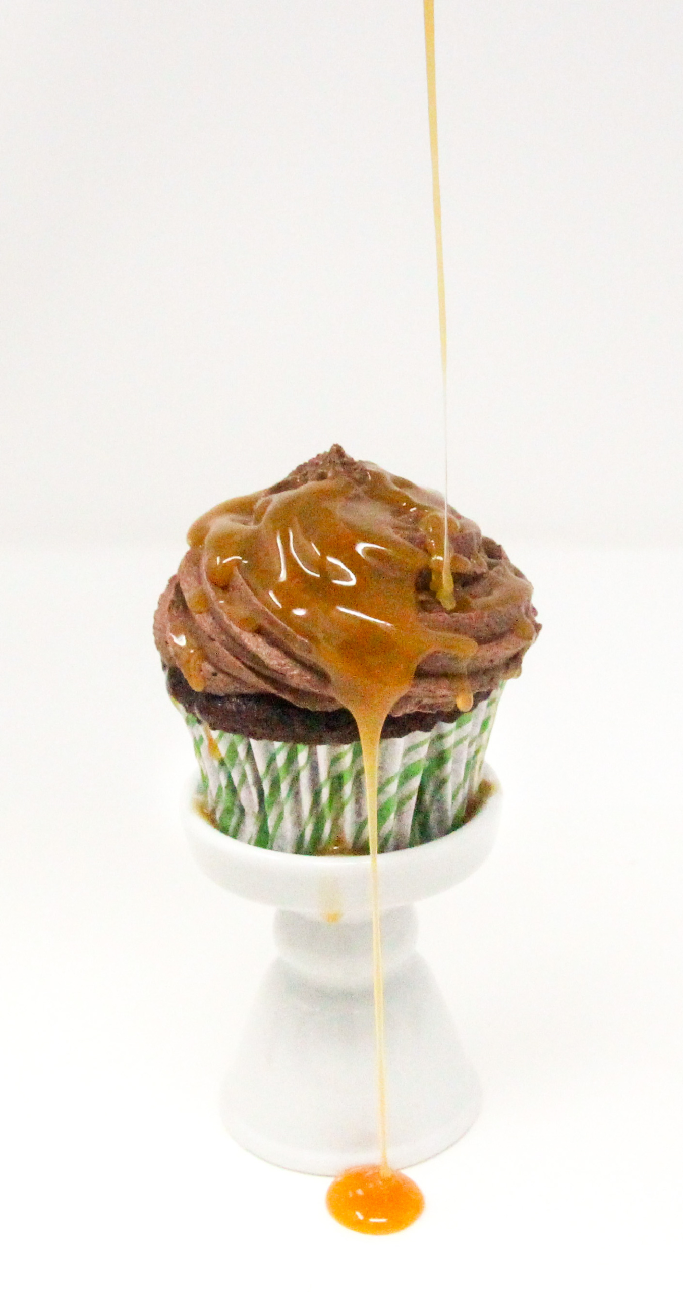 Christmas Caramel Cupcakes are rich, dark chocolate cupcakes, stuffed with homemade caramel, then topped with fudgy buttercream frosting and more caramel! Recipe shared with permission granted by Christina Romeril, author of A CHRISTMAS CANDY KILLING.