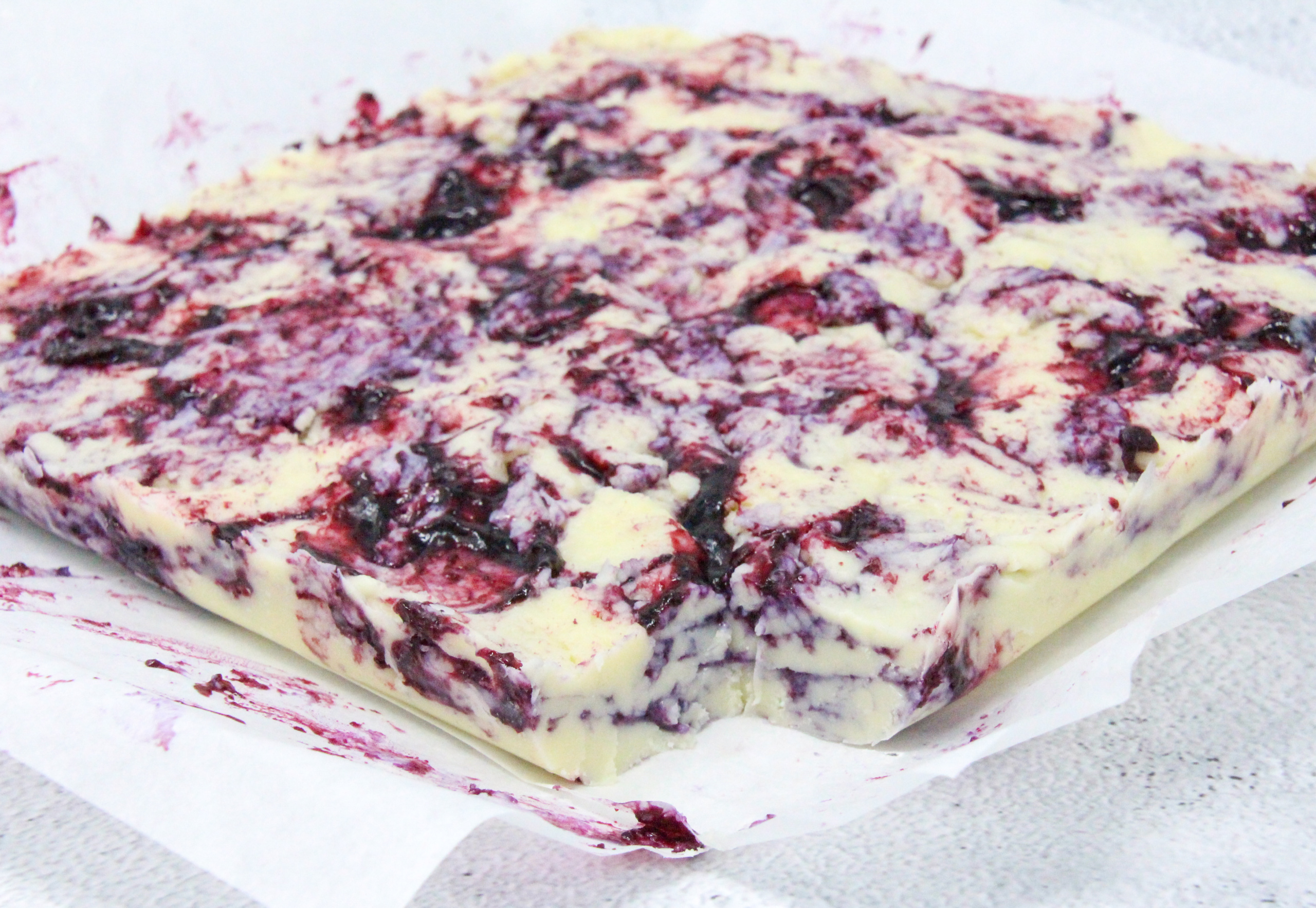 White chocolate layered with a fresh blueberry coulis combines two delectable tastes into one delicious Blueberry-and-Cream Fudge candy. Recipe shared with permission granted by Amanda Flowers, author of BLUEBERRY BLUNDER.