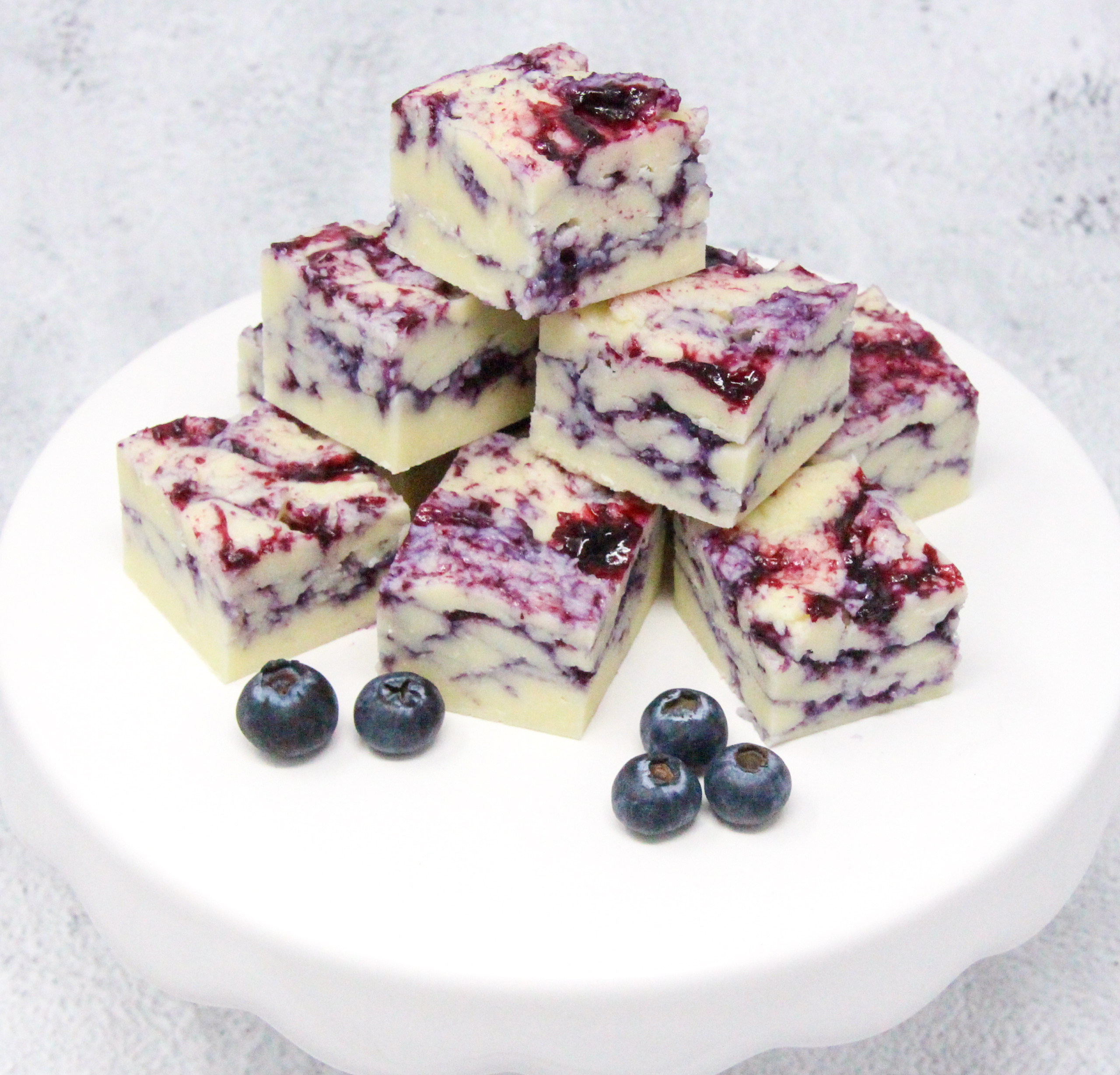 White chocolate layered with a fresh blueberry coulis combines two delectable tastes into one delicious Blueberry-and-Cream Fudge candy. Recipe shared with permission granted by Amanda Flowers, author of BLUEBERRY BLUNDER.