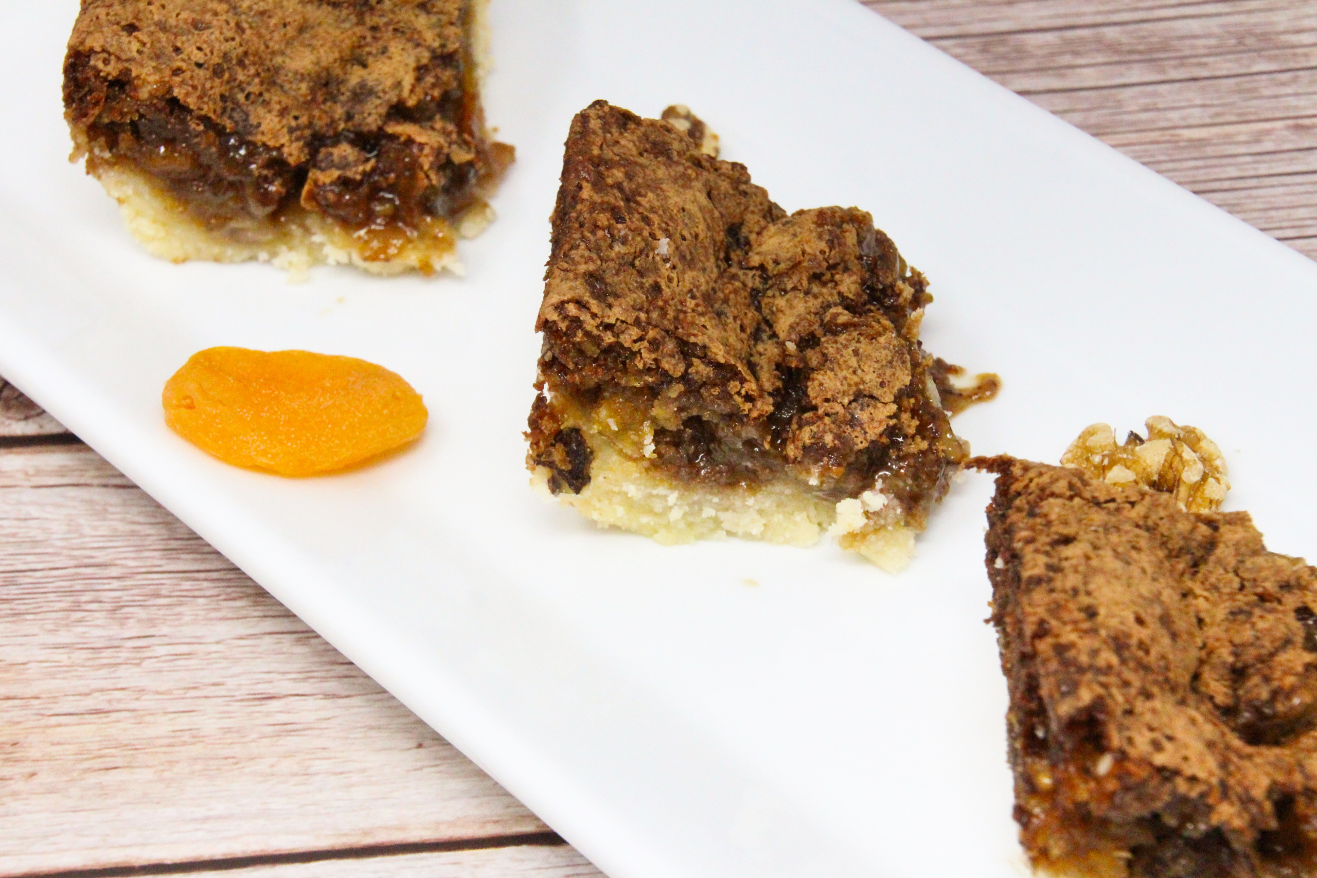 Apricot Squares start with a buttery base crust, and the filling is ooey-gooey and rich thanks to a generous portion of brown sugar, walnuts, and apricots. Recipe shared with permission granted by Barbara Ross, author of HIDDEN BENEATH. 