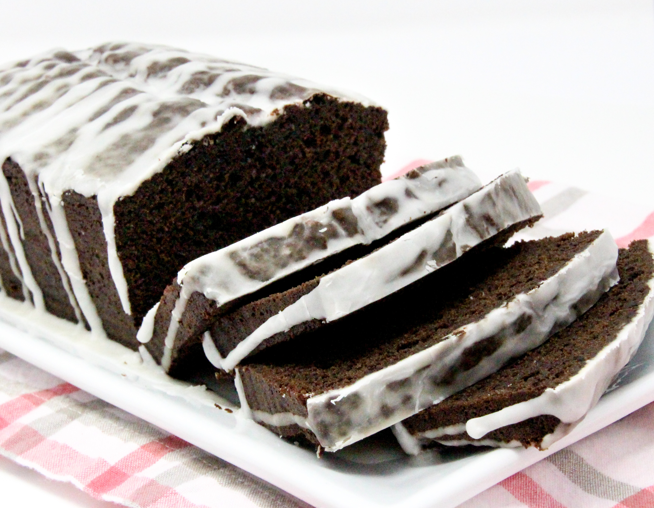 Chocolate Loaf Cake with Vanilla Drizzle has a moist crumb with a yummy chocolate flavor topped with vanilla glaze. On its own or served with ice cream, this loaf cake is a delicious way to end a meal or enjoy as a snack. Recipe shared with permission granted by Lucy Burdette, author of A CLUE IN THE CRUMBS.