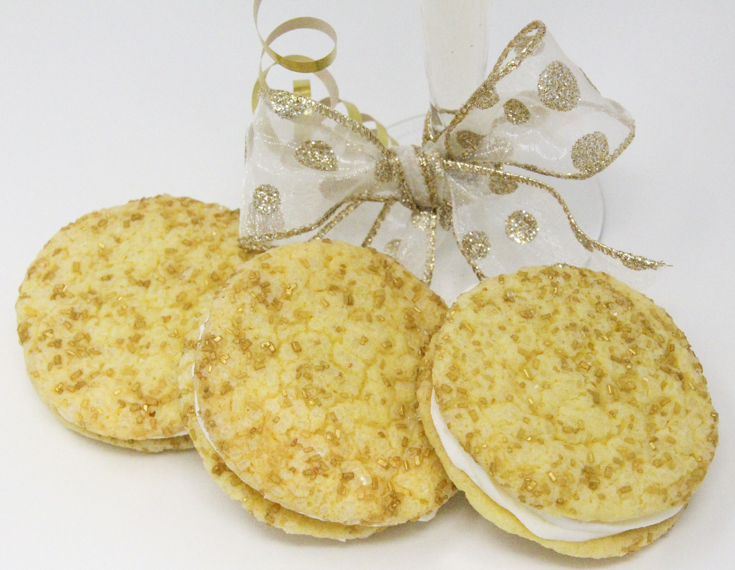 Champagne Crème Sandwich Cookies are soft-style cookies flavored with champagne and a layer of champagne-flavored buttercream. With sparkling white and gold sprinkles, these cookies will wow your guests and add a festive touch to your dessert table. Recipe created by Cinnamon & Sugar for BAKE, BATTER, AND ROLL by Catherine Bruns. 
