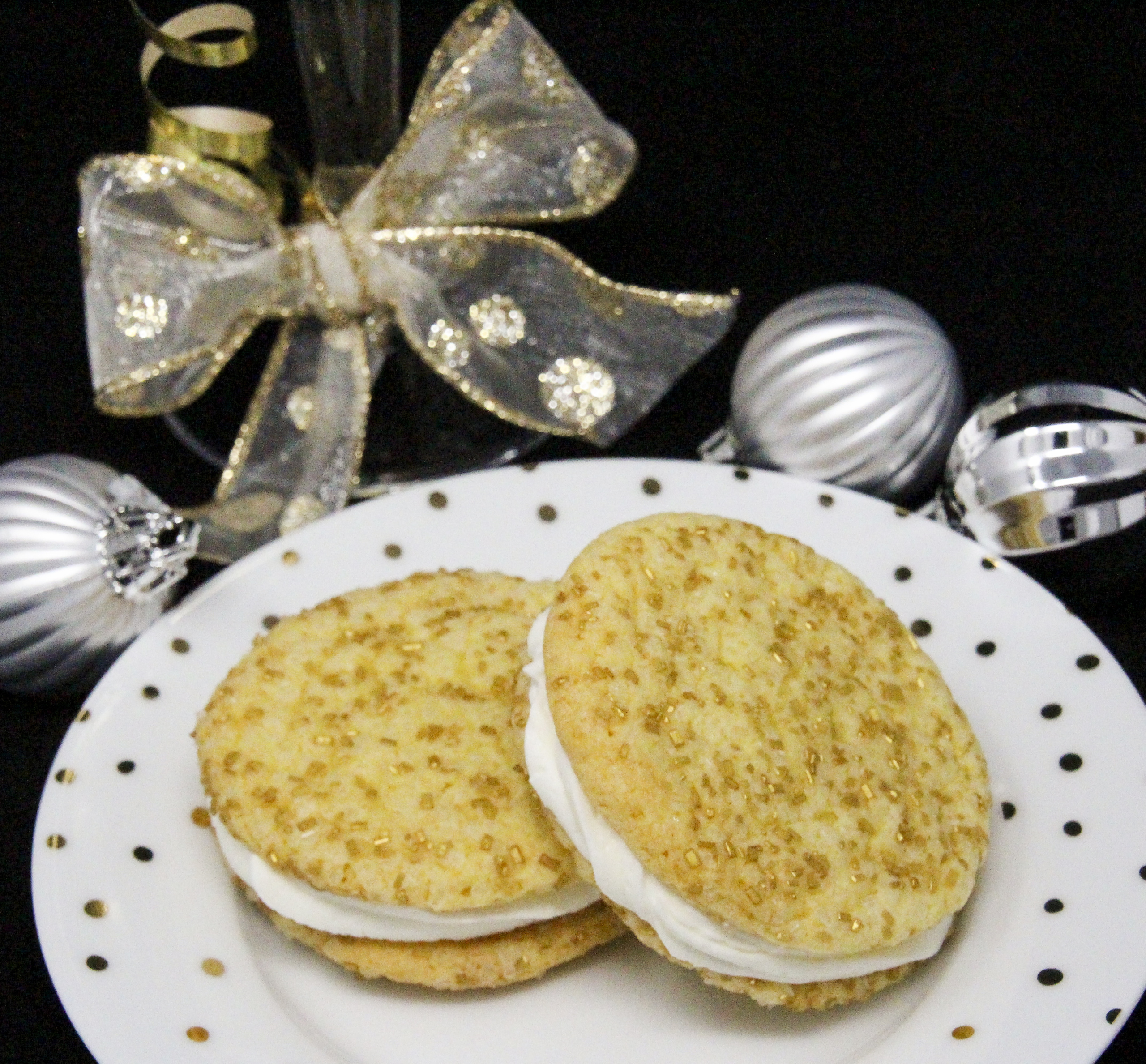 Champagne Crème Sandwich Cookies are soft-style cookies flavored with champagne and a layer of champagne-flavored buttercream. With sparkling white and gold sprinkles, these cookies will wow your guests and add a festive touch to your dessert table. Recipe created by Cinnamon & Sugar for BAKE, BATTER, AND ROLL by Catherine Bruns. 