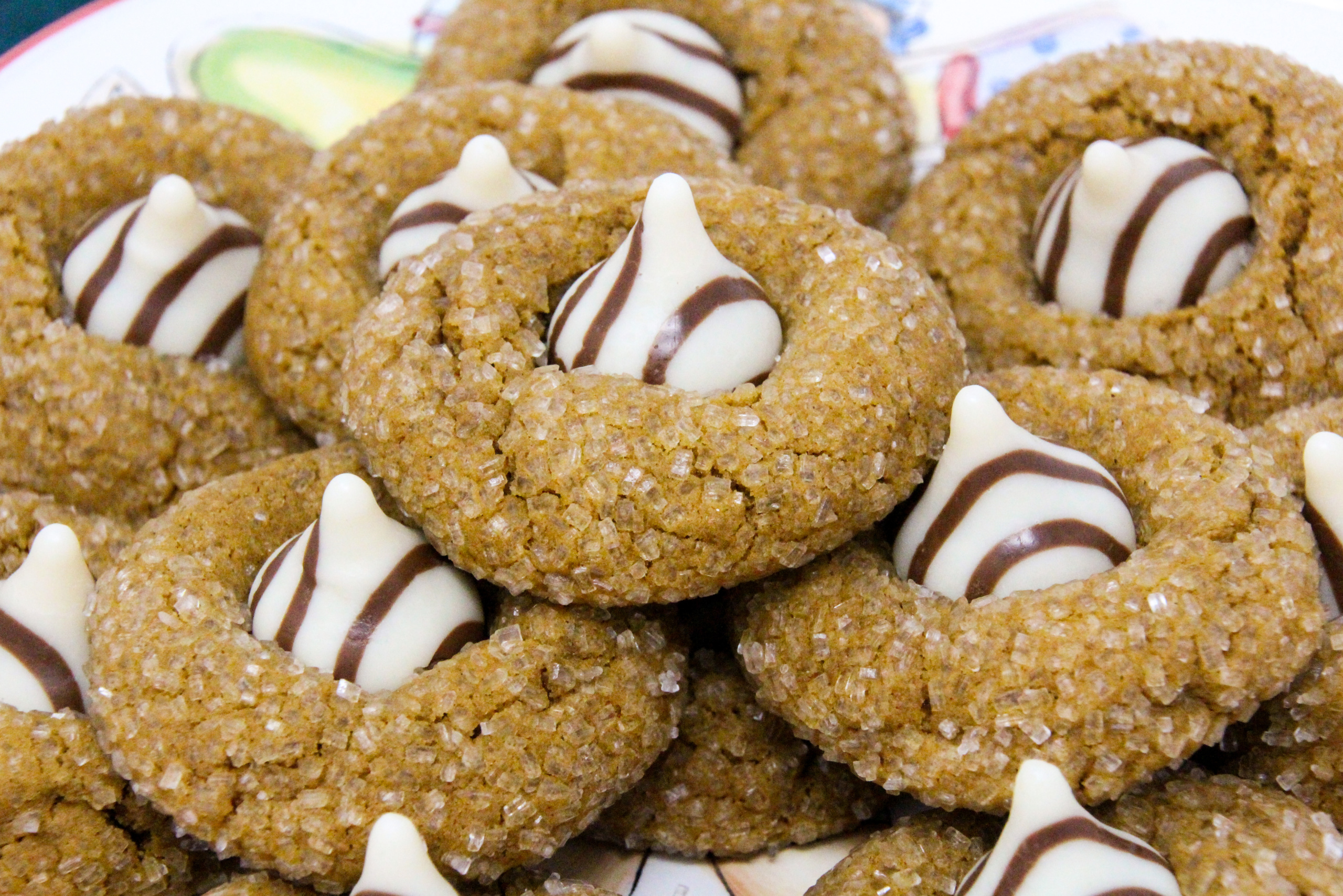 Gingerbread Kiss Cookies are spice-filled cookies topped with a white chocolate Hershey Kiss. Soft on the inside and a bit crunchy on the outside, Santa will be thrilled to find these on his cookie plate. Recipe created by Cinnamon & Sugar for EVERGREEN WISHES AT MOONGLOW by Deborah Garner. 