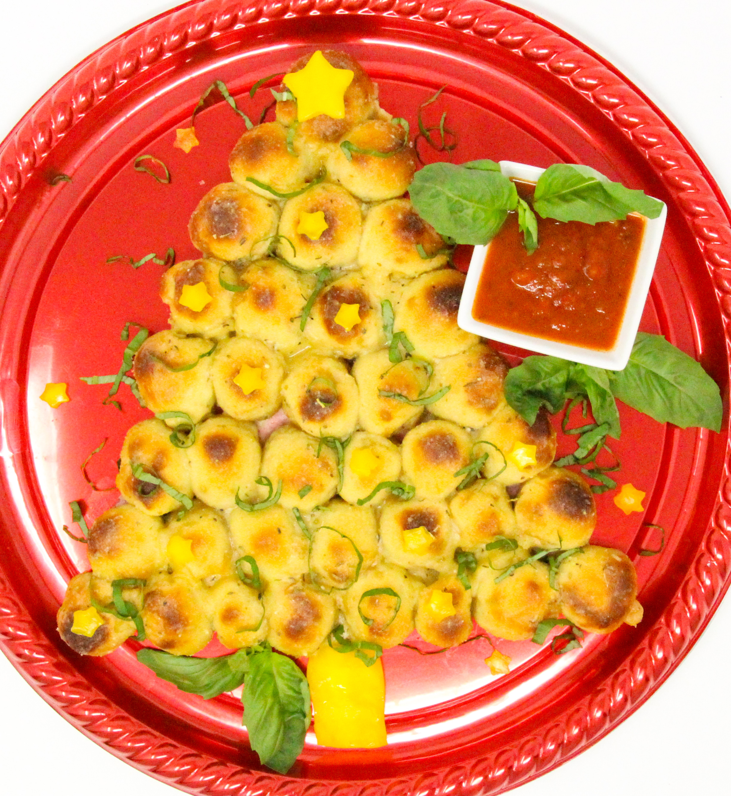 Tear-and-Share Christmas Tree Pizza Bread starts with pizza dough wrapped around chunks of mozzarella sticks, baked, then brushed with a rich combination of melted butter, Parmesan, garlic, and Italian herbs. From Sleep in Heavenly Pizza by Mindy Quigley. Copyright © 2024 by the author and reprinted by permission of St. Martin’s Publishing Group.