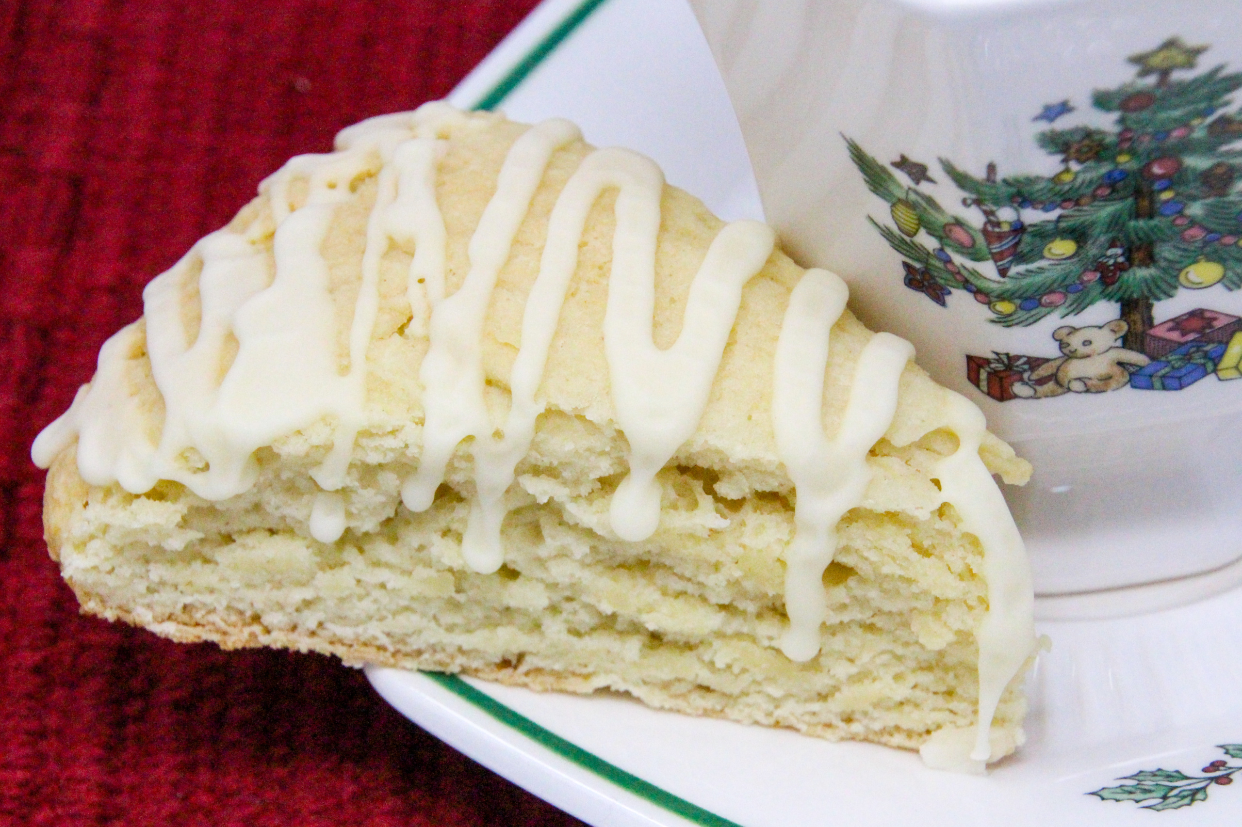 Eggnog Scones are flaky, melt-in-your-mouth pastry flavored with the quintessential holiday beverage! While the recipe doesn't use the usual huge amount of butter, the richness of the eggnog keeps these tender and with the eggnog flavored glaze, you don't even need to serve these with other accompaniments, unless you want to. Recipe shared with permission granted by Debra Sennefelder, author of A CORPSE AMONG THE CAROLERS.