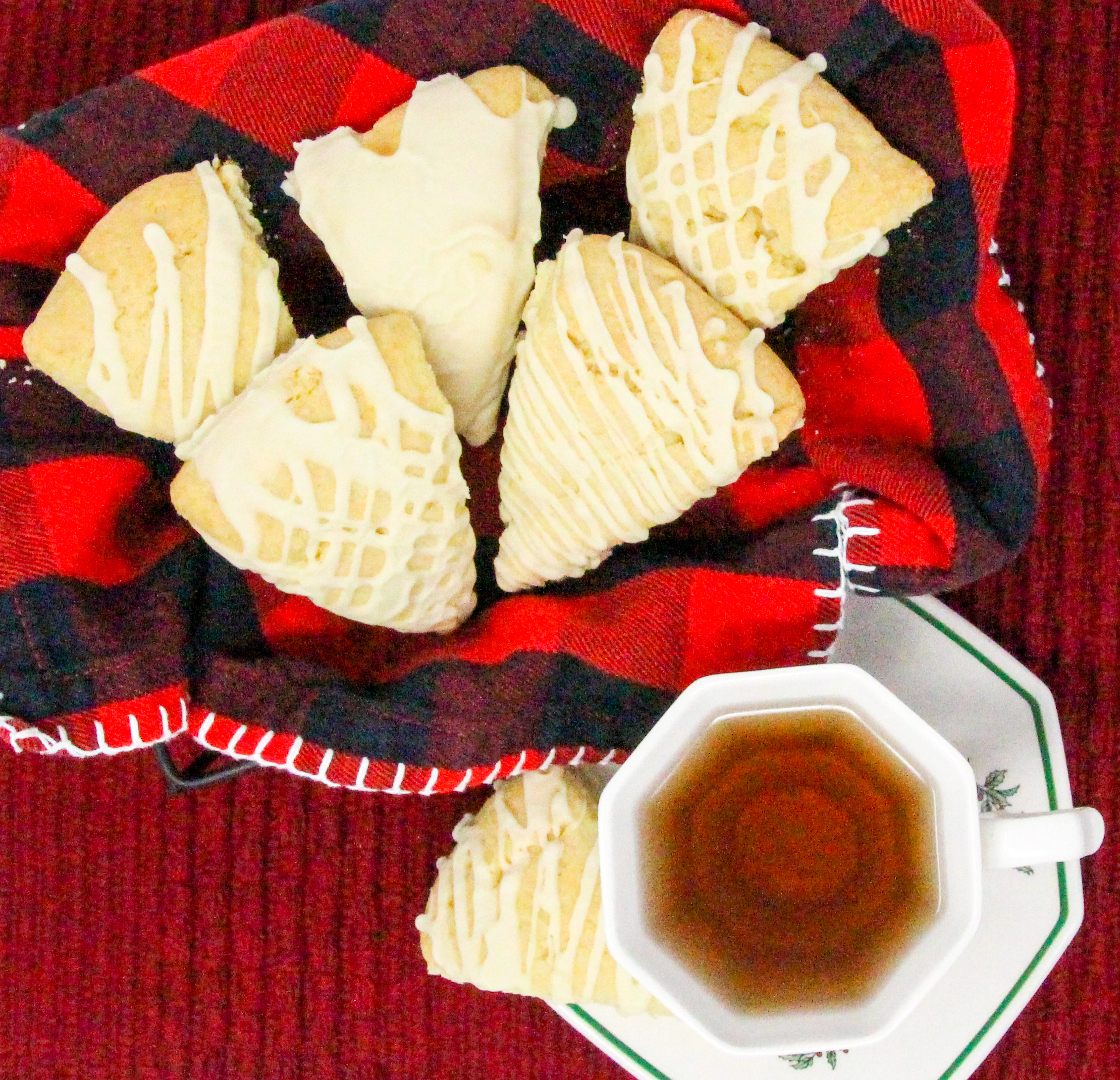 Eggnog Scones are flaky, melt-in-your-mouth pastry flavored with the quintessential holiday beverage! While the recipe doesn't use the usual huge amount of butter, the richness of the eggnog keeps these tender and with the eggnog flavored glaze, you don't even need to serve these with other accompaniments, unless you want to. Recipe shared with permission granted by Debra Sennefelder, author of A CORPSE AMONG THE CAROLERS.