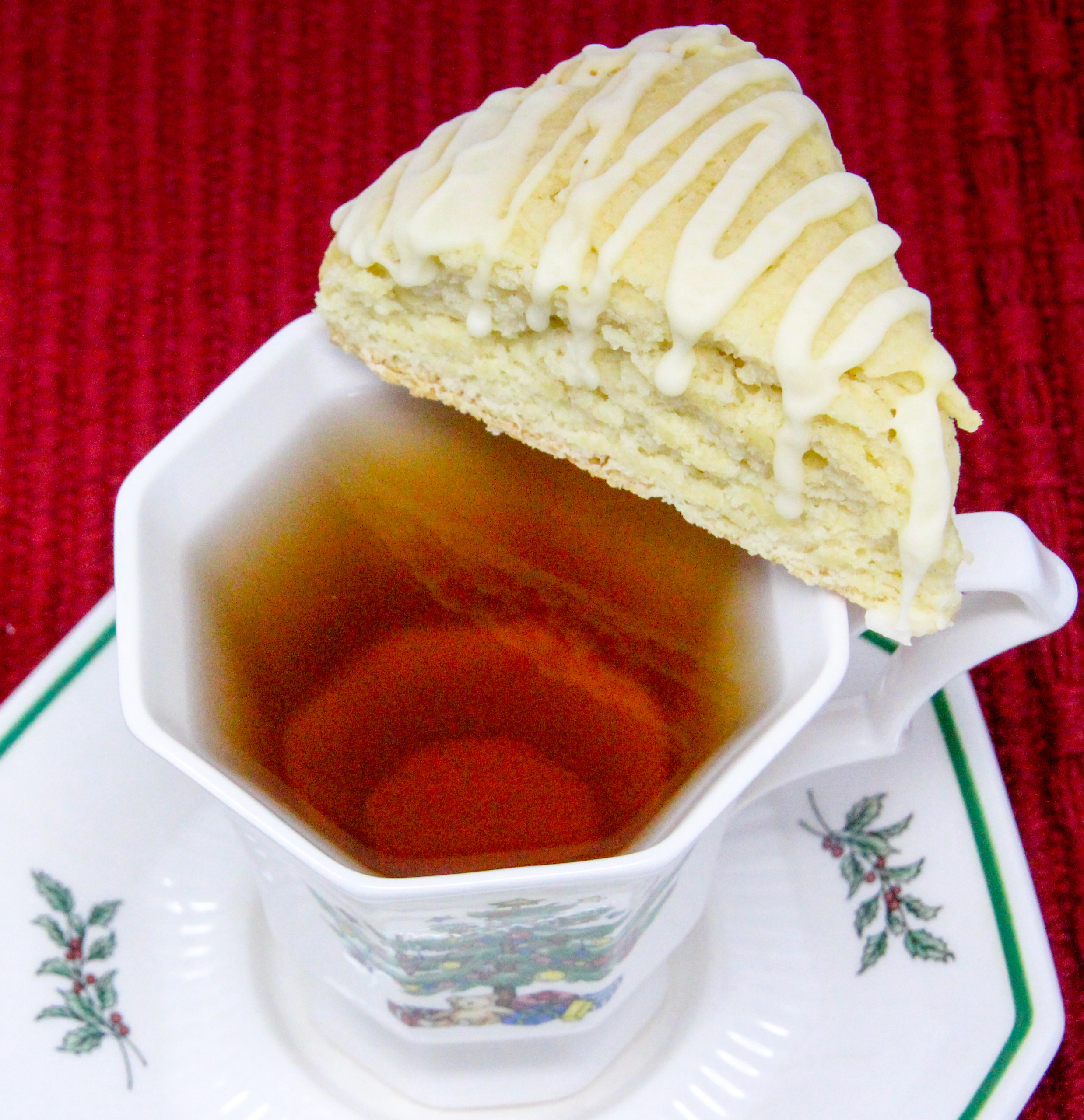 Eggnog Scones are flaky, melt-in-your-mouth pastry flavored with the quintessential holiday beverage! While the recipe doesn't use the usual huge amount of butter, the richness of the eggnog keeps these tender and with the eggnog flavored glaze, you don't even need to serve these with other accompaniments, unless you want to. Recipe shared with permission granted by Debra Sennefelder, author of A CORPSE AMONG THE CAROLERS.