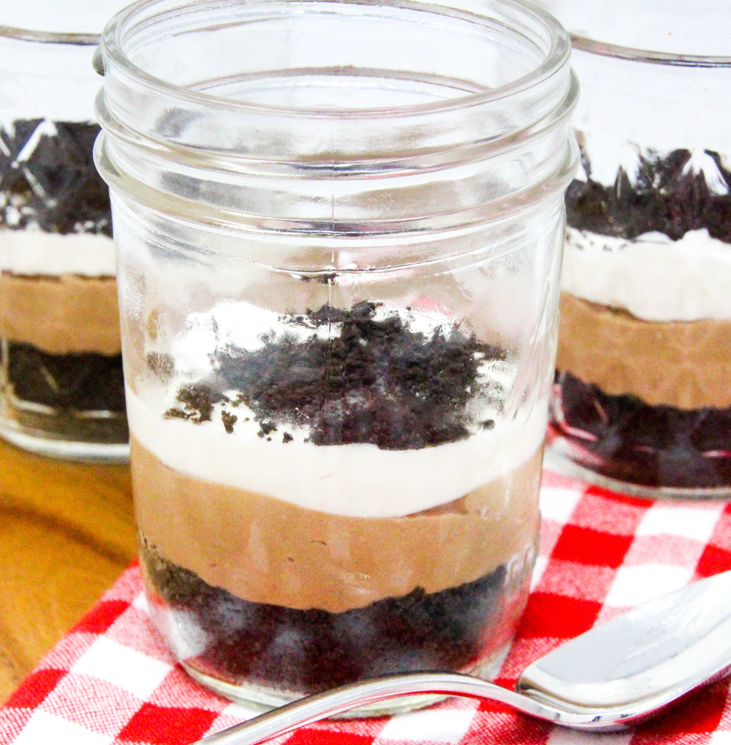 No-Bake Chocolate Cheesecake Jars are super easy-peasy to make with an Oreo crumb base. The delectable combination of chocolate, cream cheese, cream, sugar, and vanilla creates a silky layer of chocolate cheesecake, topped by cream cheese whipped cream. Layered in small mason jars, the presentation is fun and practical for easy serving for gatherings. Recipe shared with permission granted by Korina Moss, author of BAIT AND SWISS.