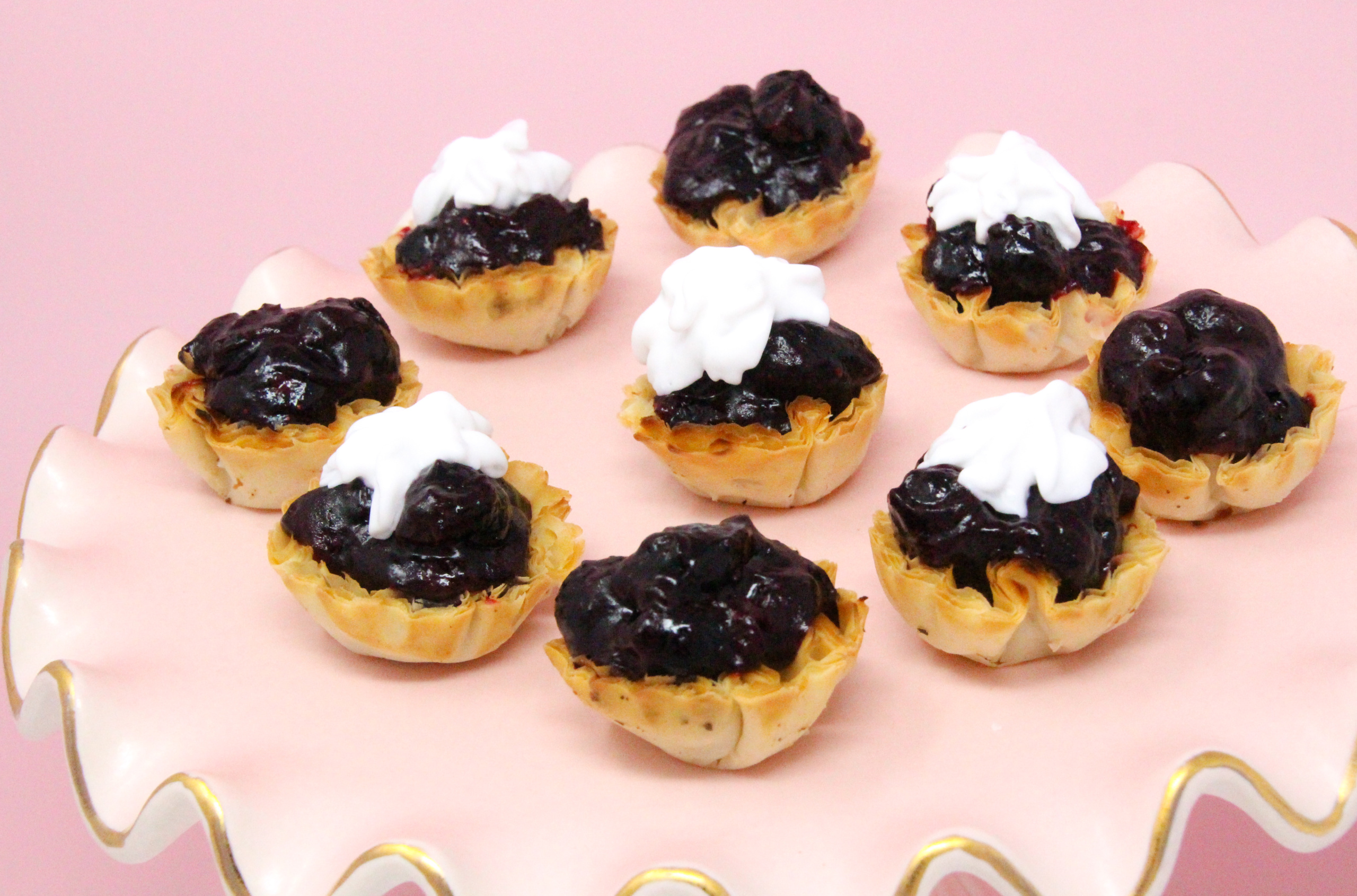 Simple blueberry tarts start with the convenience of frozen mini tart shells, then filled with fresh blueberries lightly sweetened and given added flavor with tart lemon juice. These bite-sized morsels are delicious and easy to make and serve! Recipe shared with permission granted by Daryl Wood Gerber, author of MURDER BY THE MILLIONS.