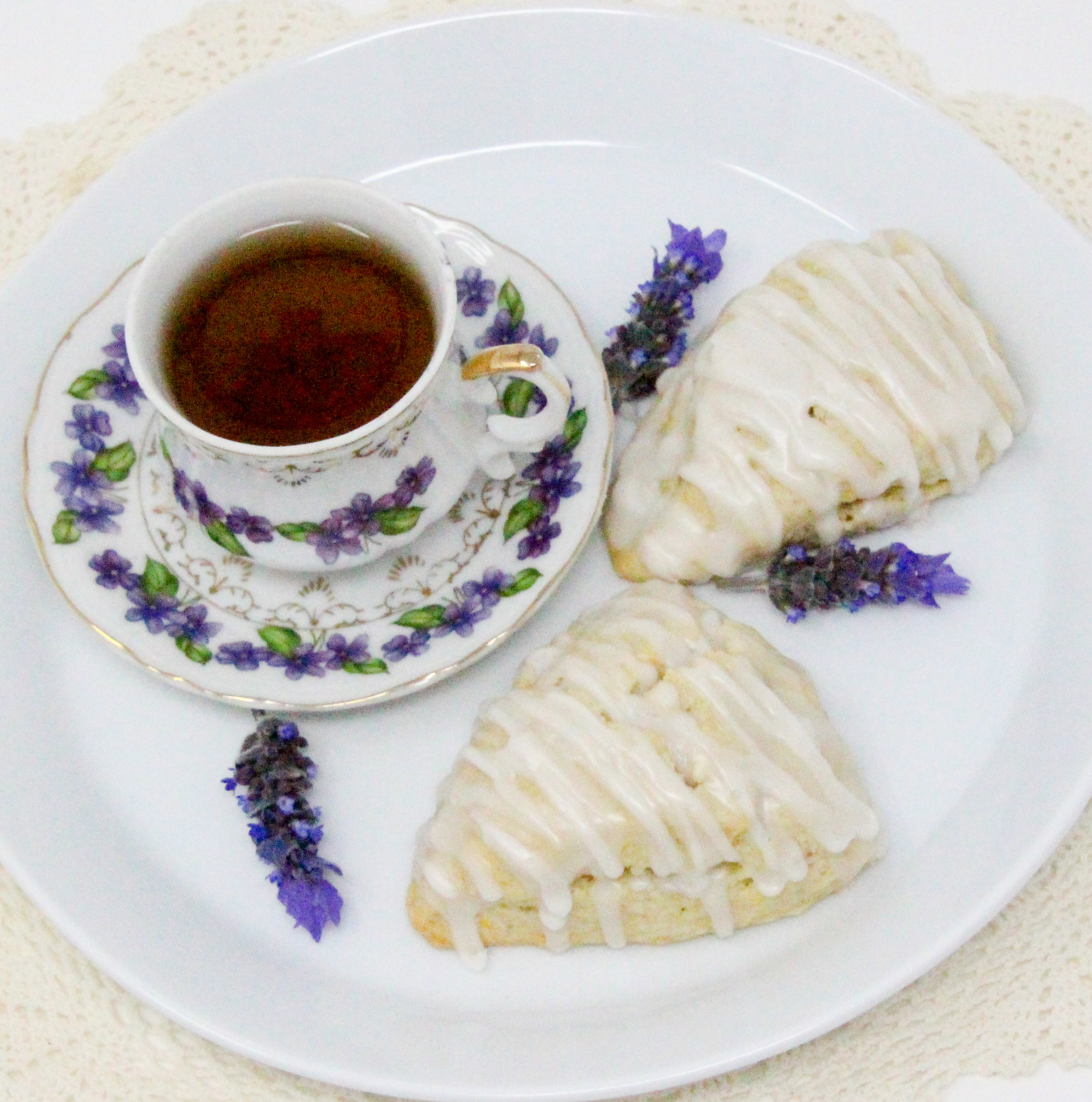 Lavender Buttermilk Scones uses the process of grating the cold butter into the flour mixture to make the scones tender. With the addition of lemon zest alongside the lavender and a drizzle of lavender lemon icing over the tops, these delectable scones were scrumptious! Recipe shared with permission granted by Leslie Budewitz, author of LAVENDER LIES BLEEDING.