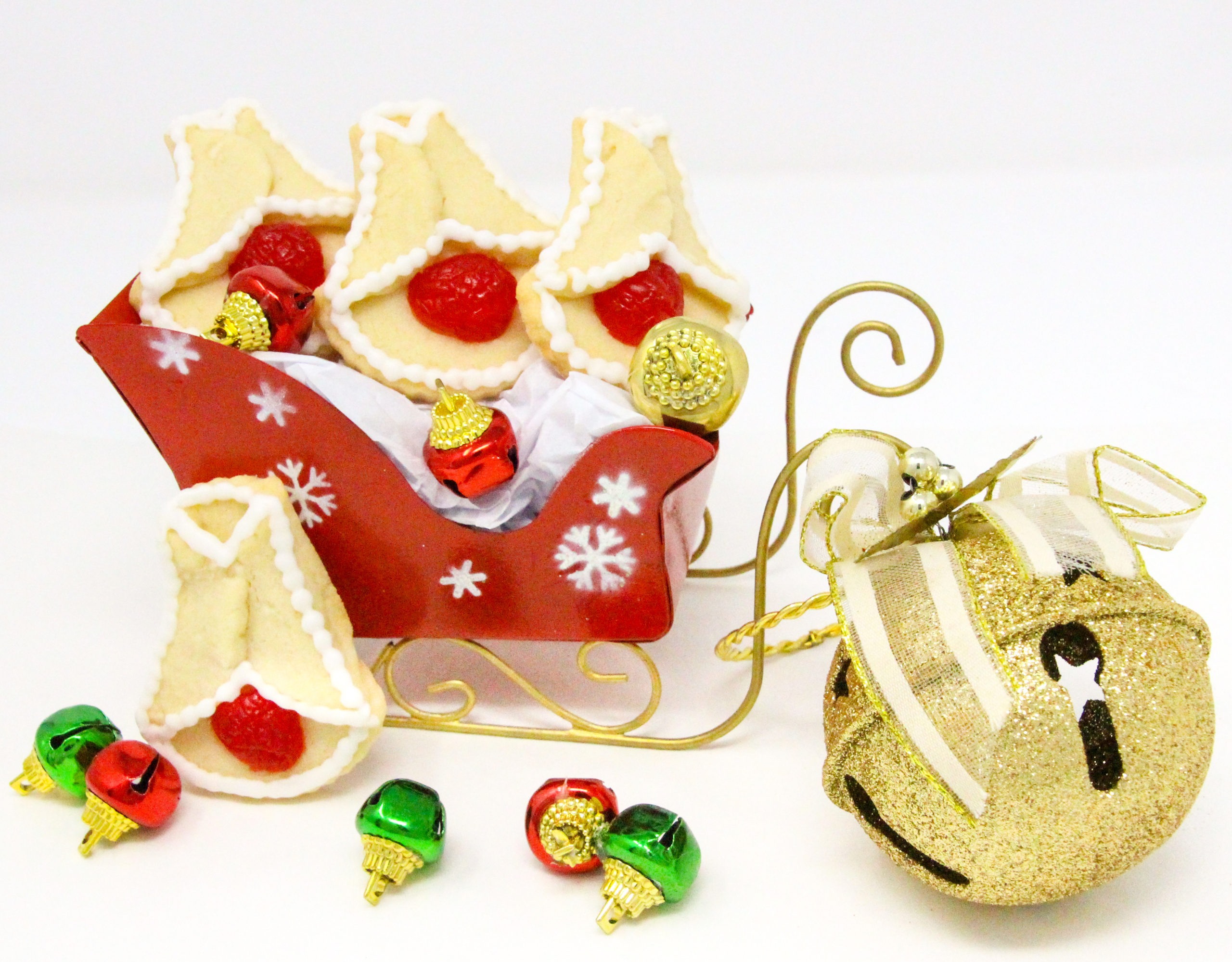 Cherry Bell Christmas Cookies start with a simple almond-flavored sugar cookie base, and are accented with halved maraschino cherries. These cookies will bring a touch of nostalgia to any holiday cookie platter and don't forget a plateful for Santa and his elves as well! Recipe created by Cinnamon & Sugar for SLEIGH BELLS AT MOONGLOW by Deborah Garner.