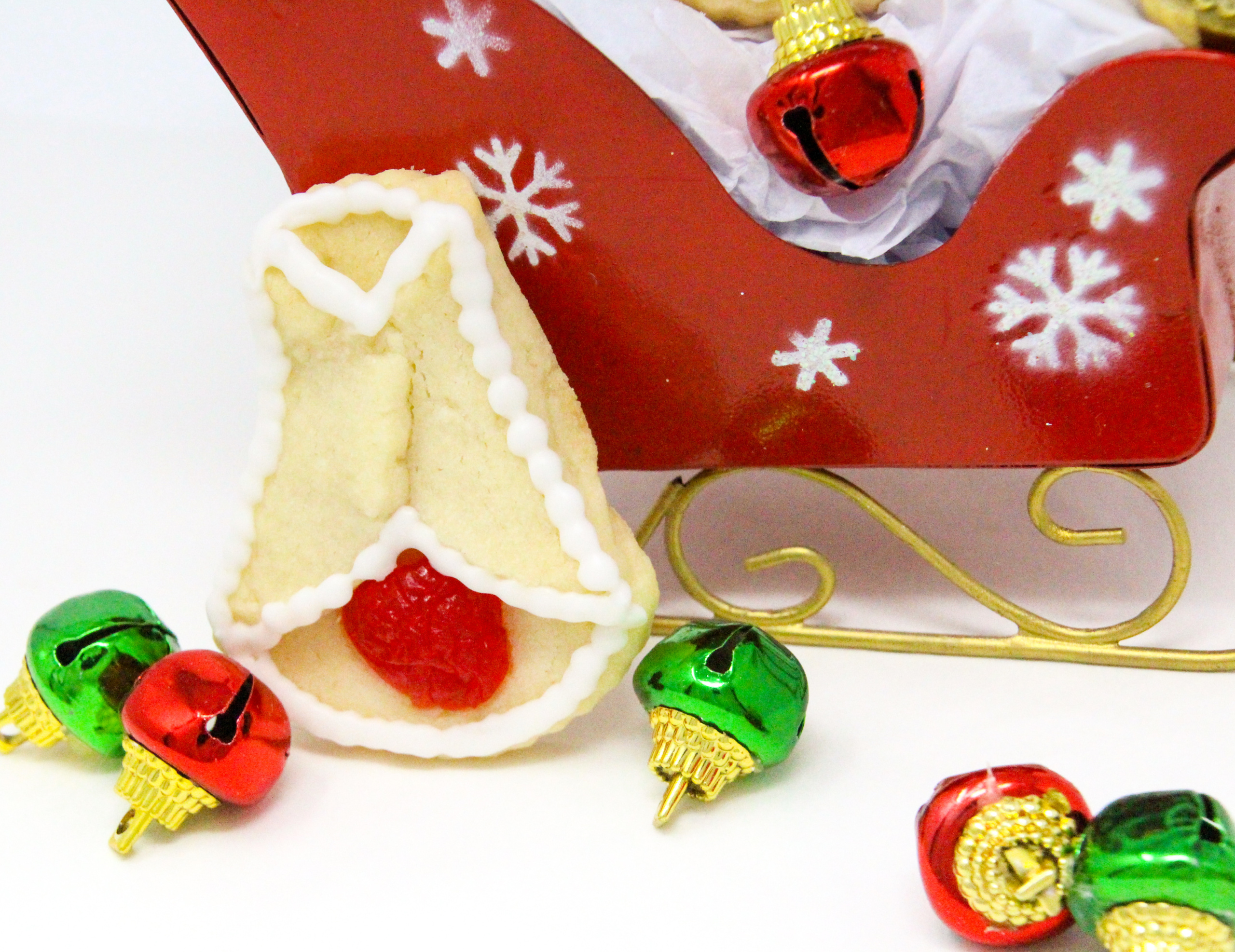 Cherry Bell Christmas Cookies start with a simple almond-flavored sugar cookie base, and are accented with halved maraschino cherries. These cookies will bring a touch of nostalgia to any holiday cookie platter and don't forget a plateful for Santa and his elves as well! Recipe created by Cinnamon & Sugar for SLEIGH BELLS AT MOONGLOW by Deborah Garner.