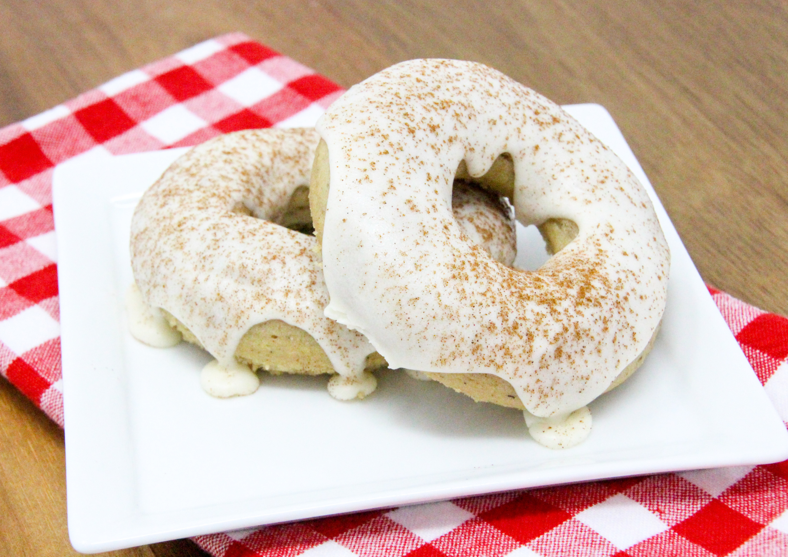 Spiced-Tea Baked Donuts have a rich flavor thanks to a generous amount of warming spices, while the sour cream frosting and sprinkled cinnamon adds a delicious element. These are delicious for breakfast or a coffee break snack! Recipe shared with permission granted by Ginger Bolton, author of SOUR CRIME DONUTS.