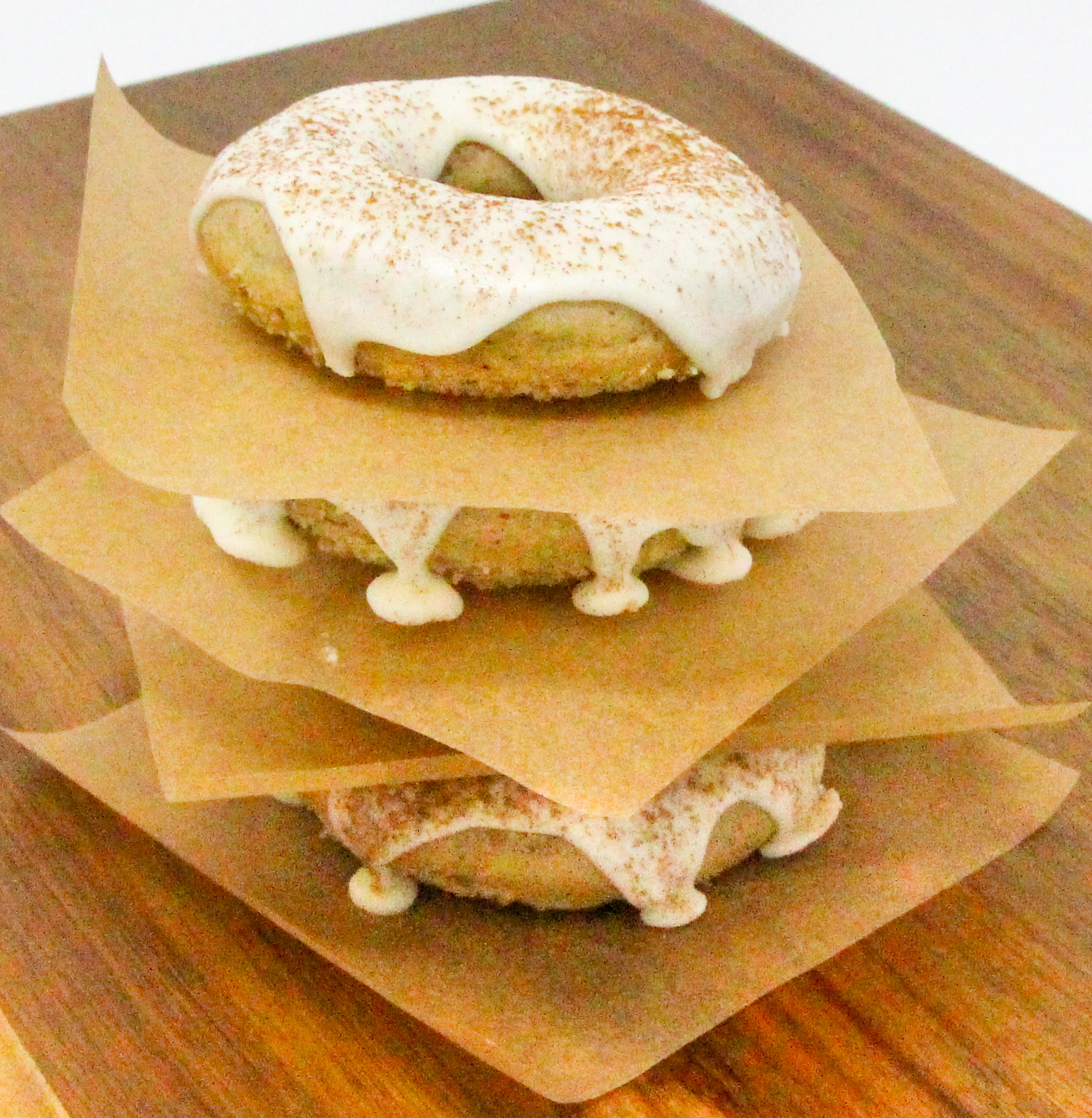 Spiced-Tea Baked Donuts have a rich flavor thanks to a generous amount of warming spices, while the sour cream frosting and sprinkled cinnamon adds a delicious element. These are delicious for breakfast or a coffee break snack! Recipe shared with permission granted by Ginger Bolton, author of SOUR CRIME DONUTS.